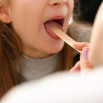 Otorhinolaryngologist examines child girl with sore throat. Treatment of throat in children and pharyngitis concept